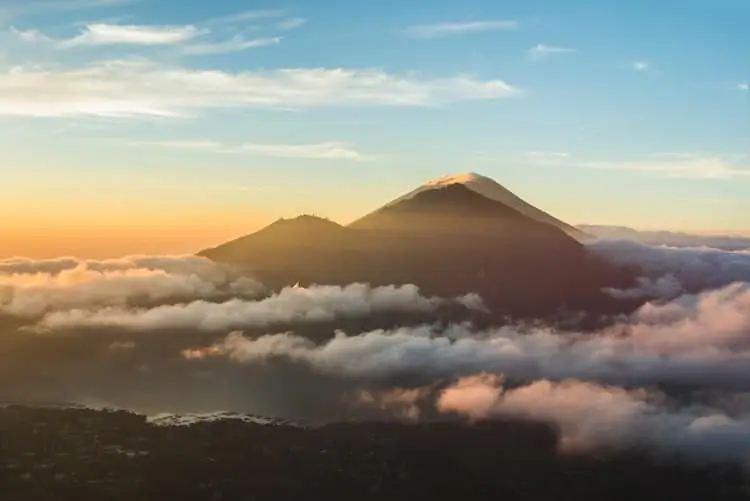 mountain range peering out from clouds at sunrise