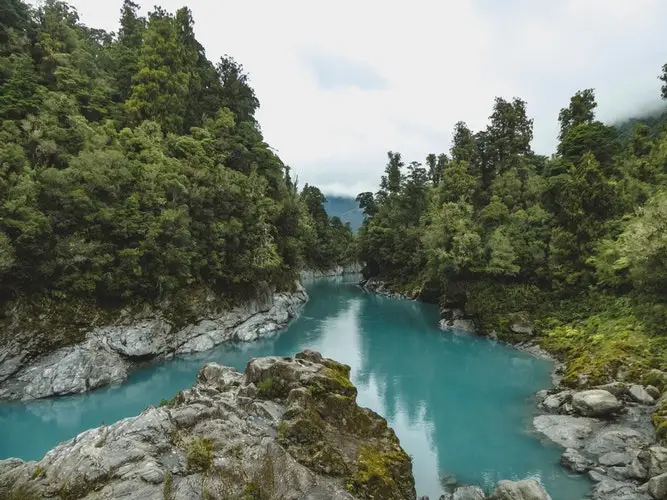 blue/green stream surrounded by rocks and trees