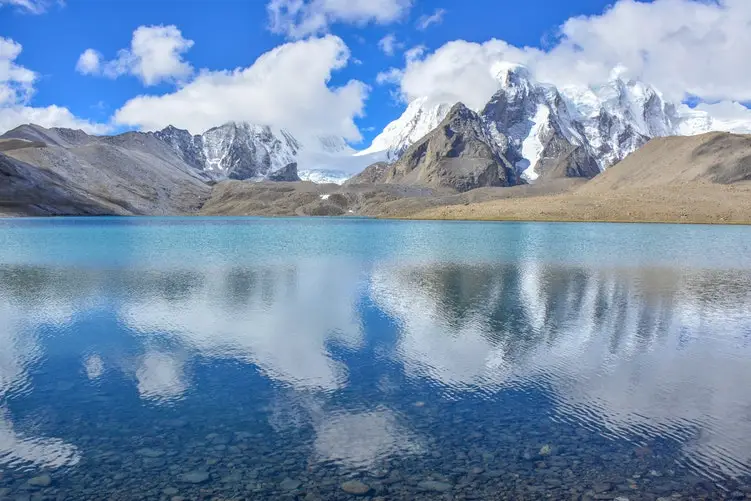 reflection of mountains and clouds in stream