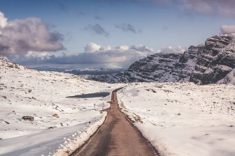 road surrounded by snow and mountain range