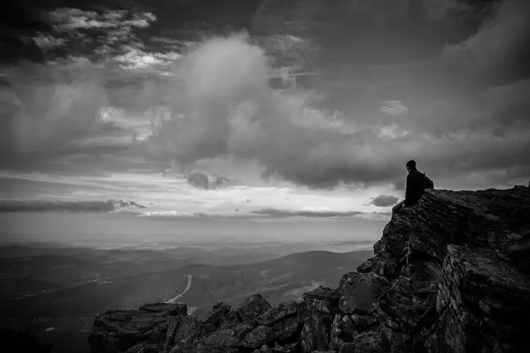 hiker sitting on edge of cliff enjoying view