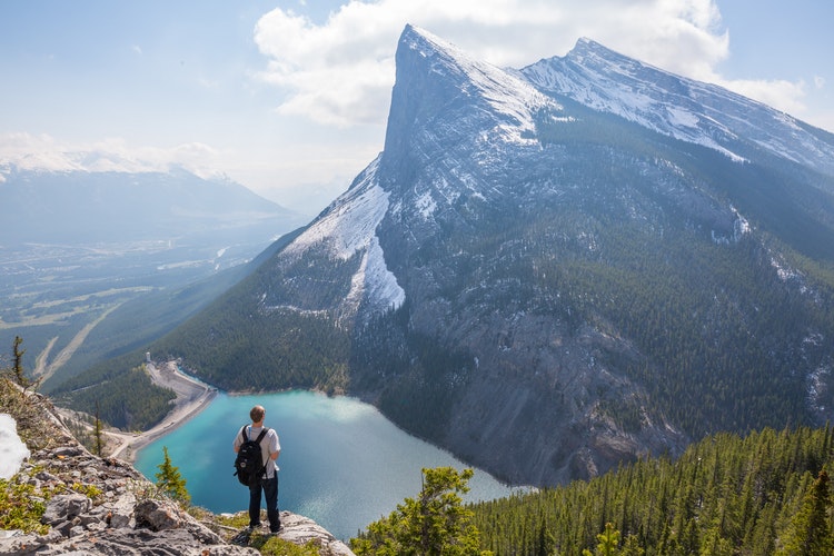 backpacker looking at view of mountain and stream