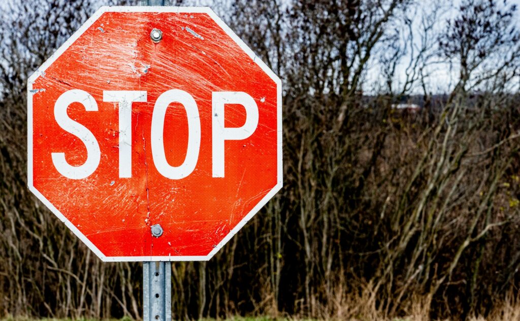 red stop sign in front of bush