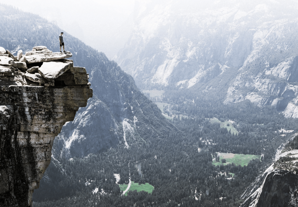 man standing on edge of steep mountain cliff