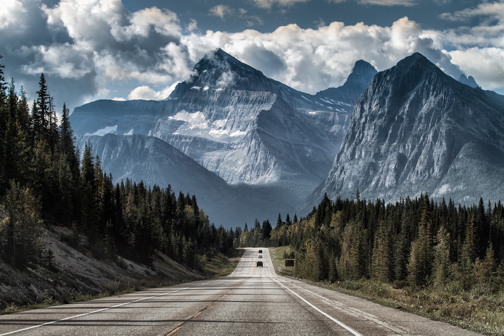 cars driving down road towards mountains