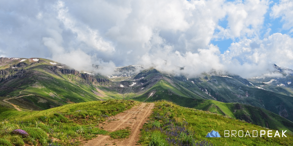 dirt path fading over a mountain with clouds