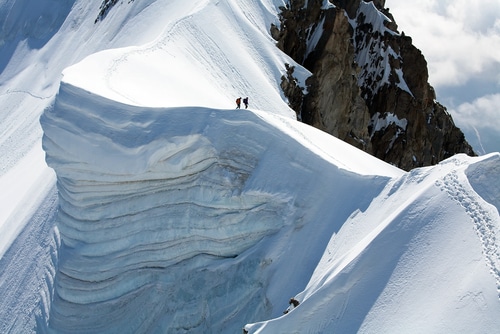 two people standing on the edge of a mountain ridge